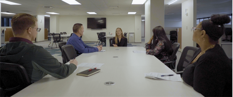 five people sitting at a table, meeting in the office