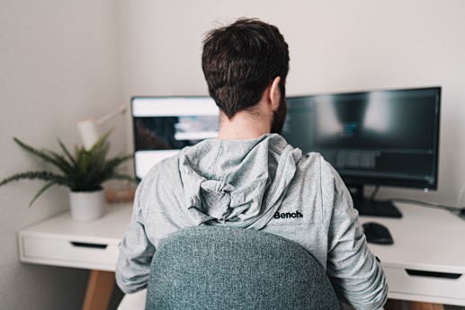 person sitting at desk in front of two monitors