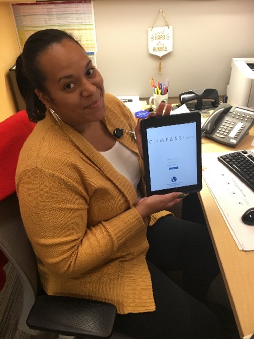 woman sitting at office desk, holding mobile tablet